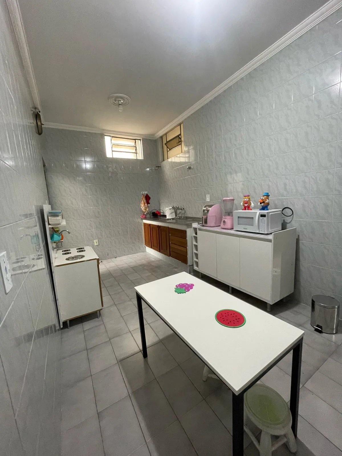 Cozinha das oficinas com bancada, fogão, micro-ondas e mesa branca com banquinhos